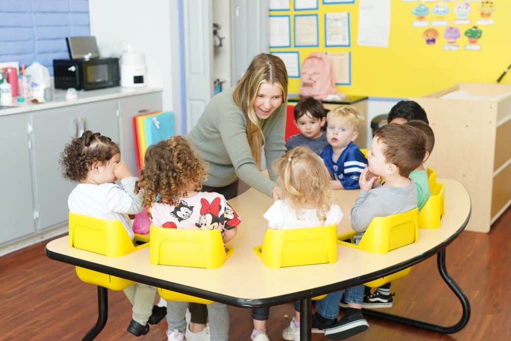 Happy children smiling with their teacher in the classroom at Creative Learners Child Care in Pleasanton, CA. Caring staff in our daycare.